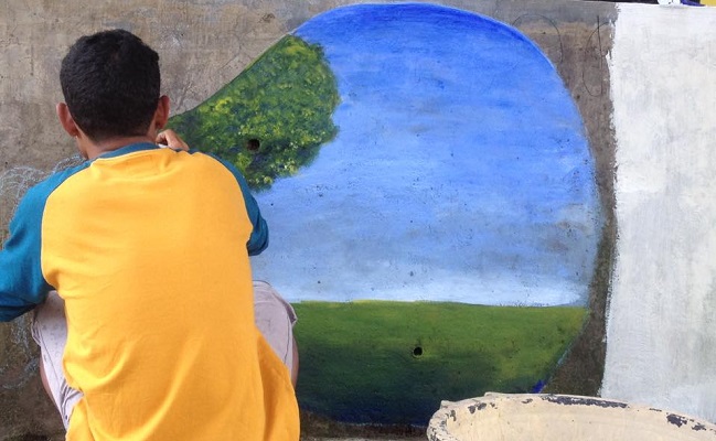 Matheus Zakeus sedang melukis di salah satu dinding di dalam kompleks SMAK St Fransiskus